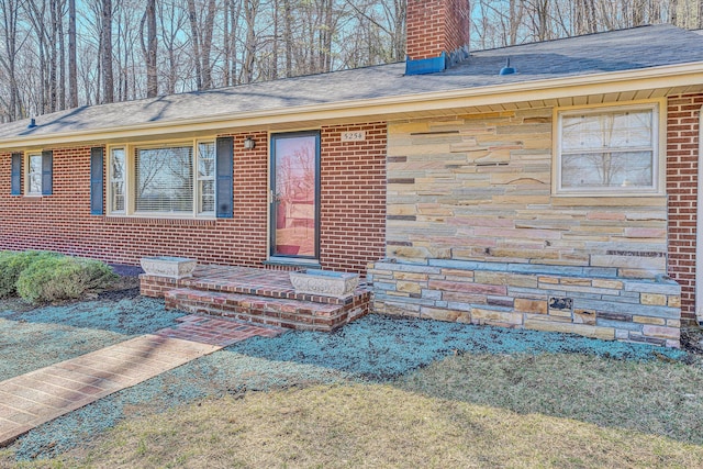 doorway to property with brick siding, stone siding, and a chimney