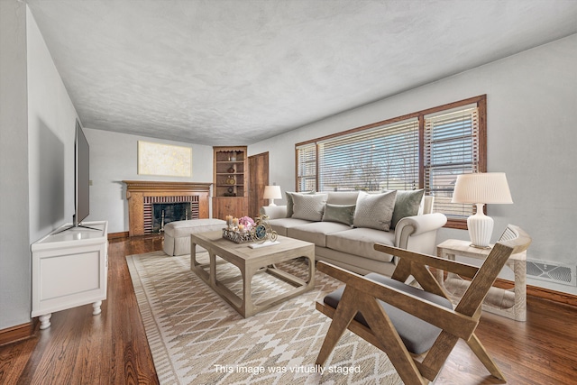 living area with baseboards, a brick fireplace, and wood finished floors