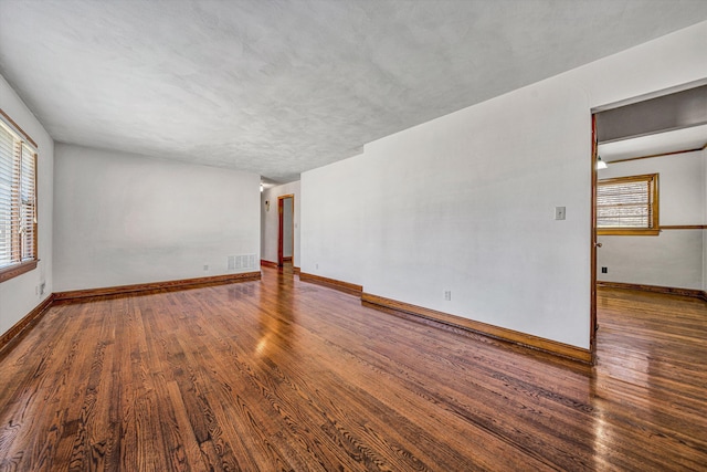 empty room featuring visible vents, baseboards, and wood finished floors