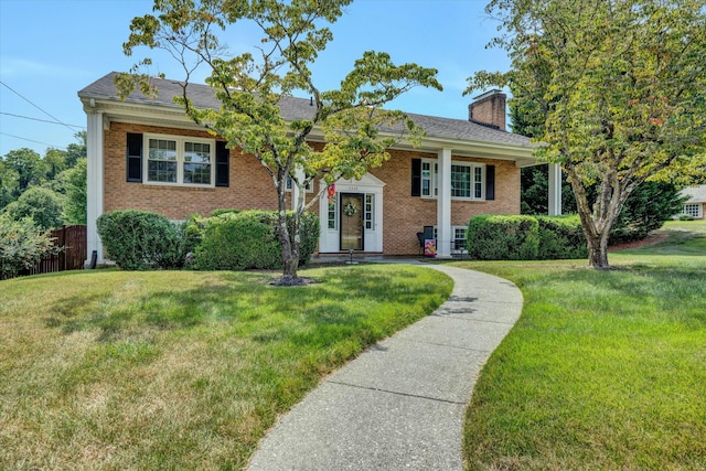 bi-level home featuring a front yard, brick siding, and a chimney