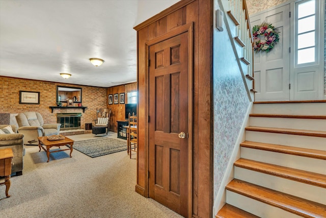 stairway with carpet flooring, a fireplace, and brick wall