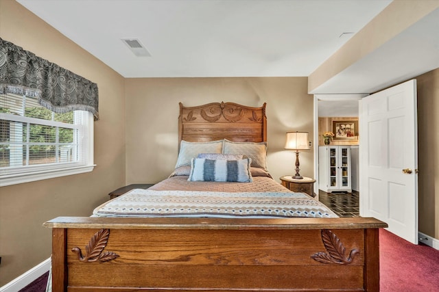 bedroom with dark colored carpet, visible vents, and baseboards