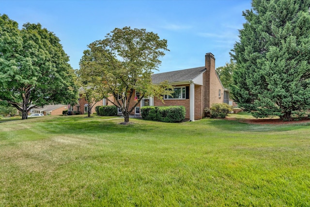 view of front of house featuring a front yard, brick siding, and a chimney