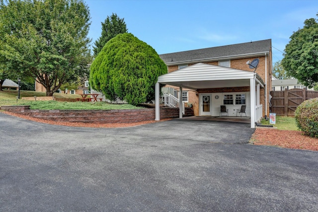 exterior space with a gate, fence, driveway, a carport, and brick siding