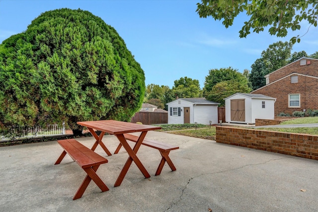 view of patio / terrace featuring an outdoor structure, fence, and a shed