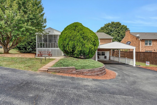 view of front of property with a detached carport, aphalt driveway, fence, and a sunroom