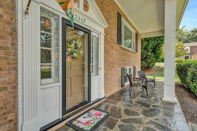 property entrance featuring brick siding and covered porch