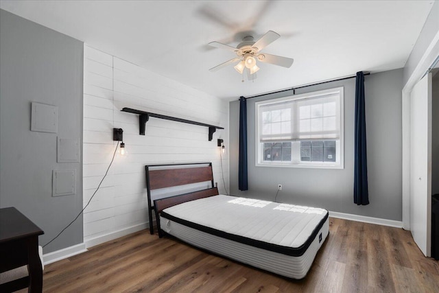 bedroom with a ceiling fan, wood finished floors, and baseboards