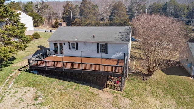 rear view of property featuring a deck, a lawn, and a chimney