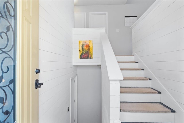 staircase featuring wooden walls