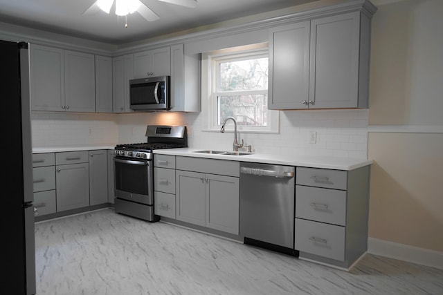 kitchen with a sink, marble finish floor, appliances with stainless steel finishes, and gray cabinetry