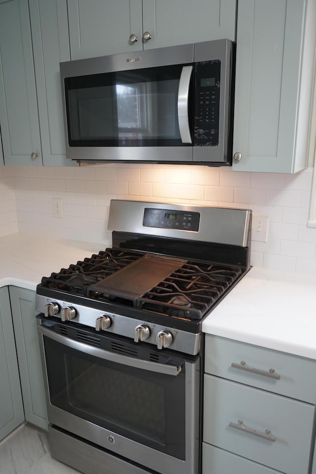 kitchen featuring tasteful backsplash, gray cabinetry, stainless steel appliances, and light countertops