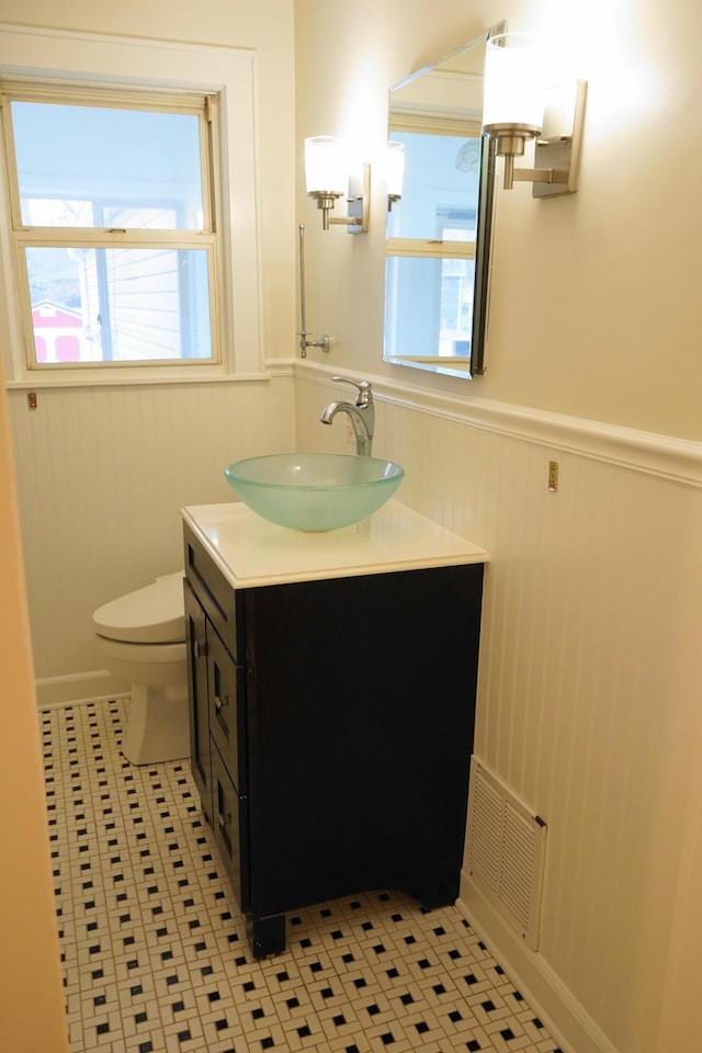 bathroom featuring a wainscoted wall, toilet, vanity, and visible vents