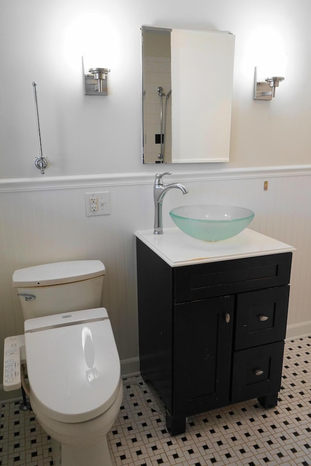 bathroom featuring tile patterned floors, a wainscoted wall, toilet, and vanity