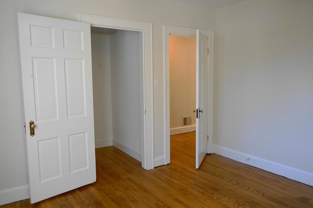 unfurnished bedroom with wood finished floors, visible vents, and baseboards