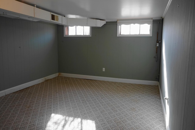 below grade area featuring wooden walls, plenty of natural light, visible vents, and baseboards