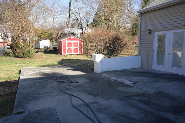 view of patio / terrace with an outdoor structure, a storage unit, french doors, and fence