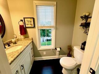 half bathroom featuring vanity, toilet, and baseboards