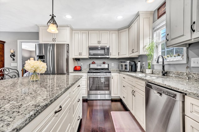 kitchen featuring recessed lighting, light stone counters, a sink, dark wood-type flooring, and appliances with stainless steel finishes