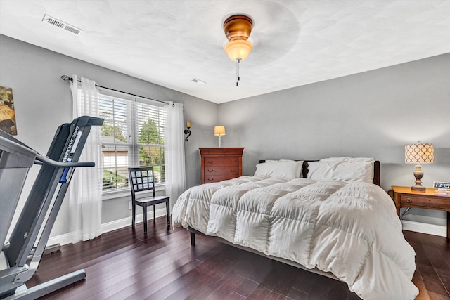 bedroom featuring baseboards, hardwood / wood-style flooring, visible vents, and a ceiling fan