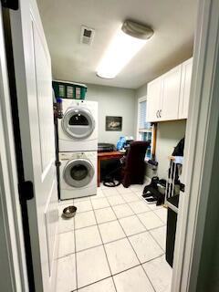 laundry area featuring light tile patterned floors, visible vents, and stacked washer / drying machine