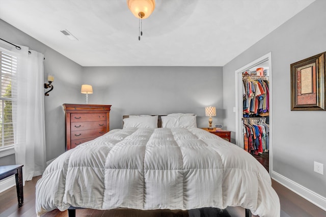 bedroom featuring baseboards, wood finished floors, a closet, and a walk in closet