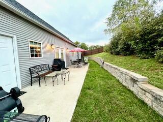 view of yard with a garage, a patio, and fence