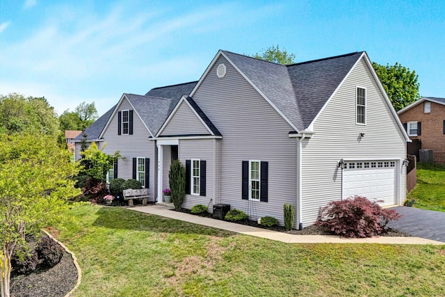 traditional home with an attached garage, driveway, a front yard, and central AC