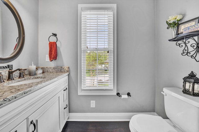 bathroom with baseboards, vanity, and toilet
