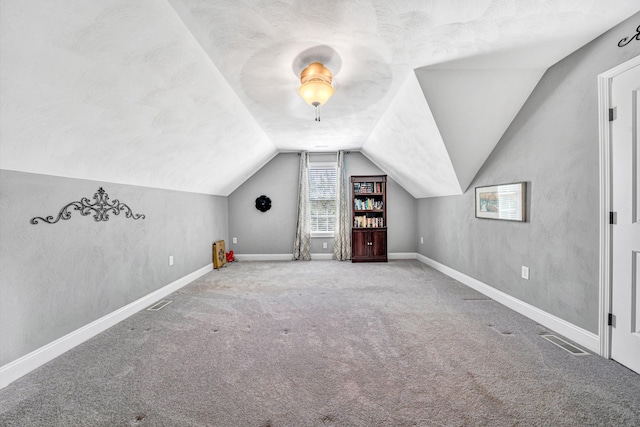 additional living space with lofted ceiling, visible vents, carpet floors, and baseboards