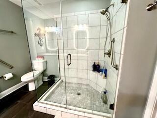 full bathroom featuring a stall shower, toilet, and wood finished floors