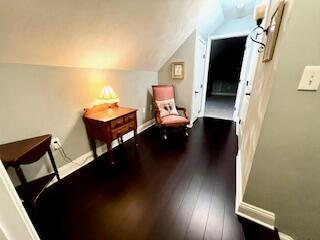 living area featuring dark wood-style floors, baseboards, and lofted ceiling