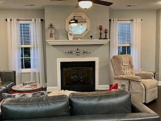 living area with a fireplace and a ceiling fan