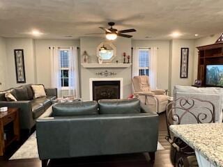 living area with recessed lighting, a ceiling fan, dark wood finished floors, and a fireplace