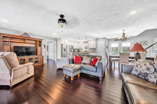 living room featuring ceiling fan with notable chandelier, baseboards, dark wood-type flooring, and recessed lighting