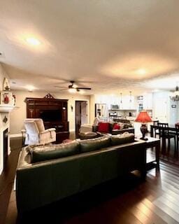 living room featuring dark wood-type flooring, a fireplace, and a ceiling fan