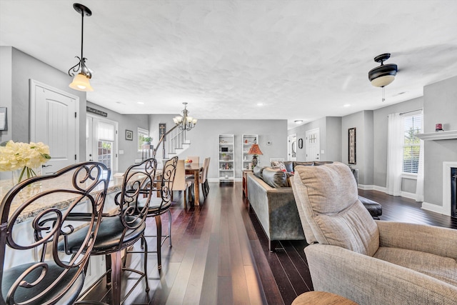 living area with recessed lighting, dark wood-style floors, baseboards, stairs, and a notable chandelier