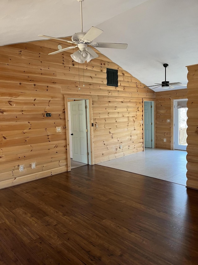 unfurnished room with visible vents, ceiling fan, wood walls, vaulted ceiling, and wood finished floors