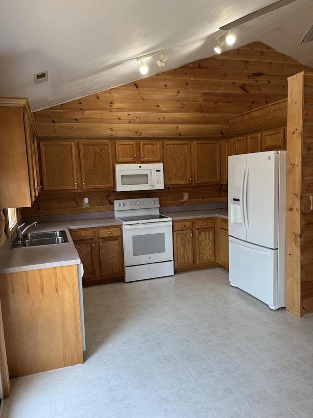 kitchen featuring brown cabinets, white appliances, lofted ceiling, and a sink