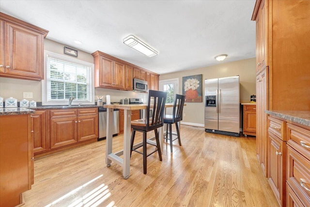 kitchen featuring a sink, light wood-style floors, brown cabinets, and stainless steel appliances