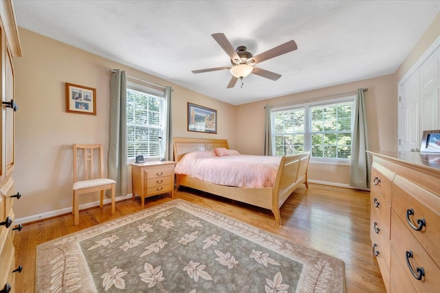 bedroom with light wood-type flooring, multiple windows, and baseboards