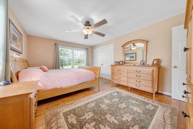 bedroom featuring a closet, baseboards, light wood-type flooring, and ceiling fan