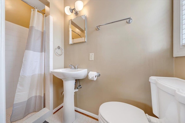 bathroom featuring baseboards, tiled shower, and toilet