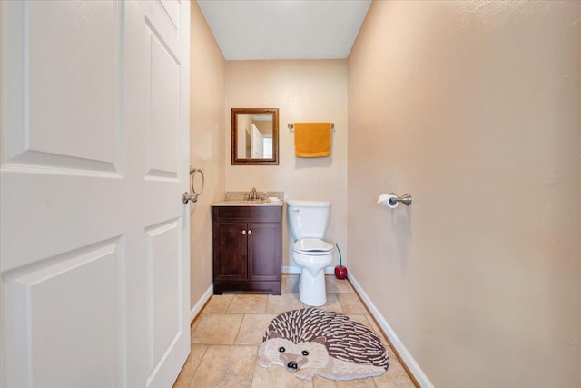 half bathroom featuring tile patterned flooring, toilet, vanity, and baseboards