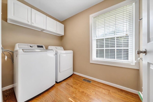 washroom featuring visible vents, baseboards, cabinet space, light wood-style floors, and independent washer and dryer