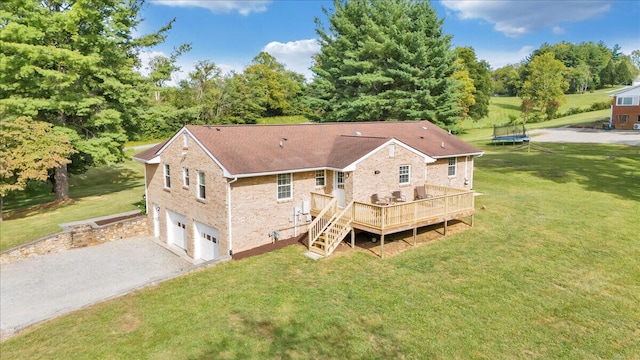 back of house featuring a deck, a trampoline, a yard, gravel driveway, and a garage