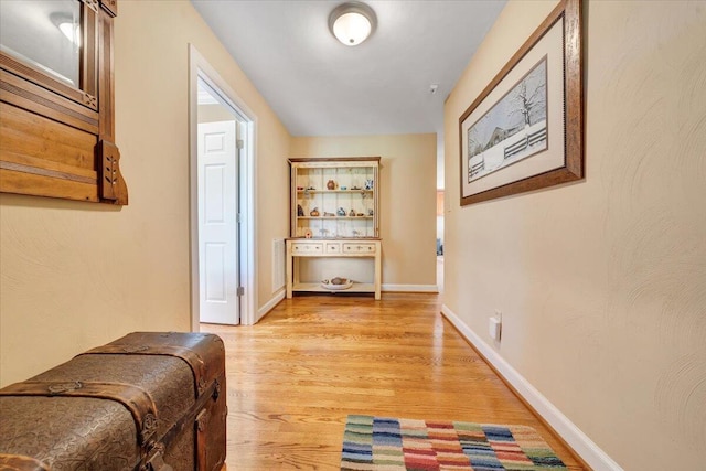 hall with light wood-style flooring and baseboards