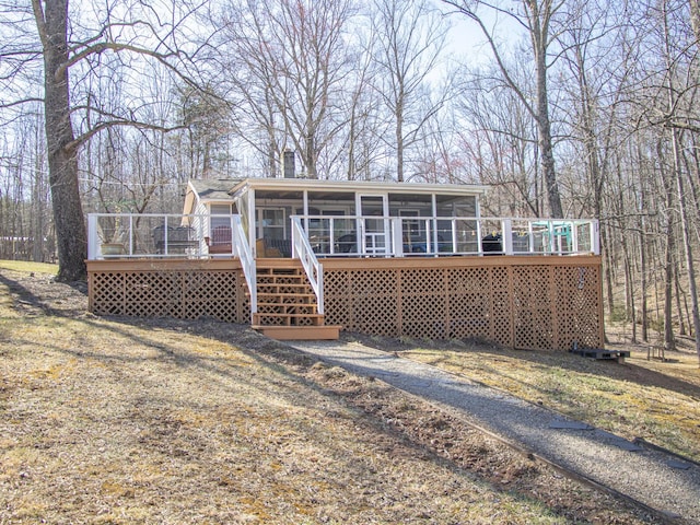 view of front of house with a deck, a sunroom, and a chimney