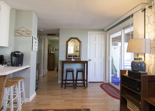 interior space with light wood finished floors, a textured ceiling, and baseboards