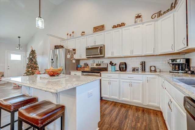 kitchen with a breakfast bar, dark wood finished floors, appliances with stainless steel finishes, and white cabinetry